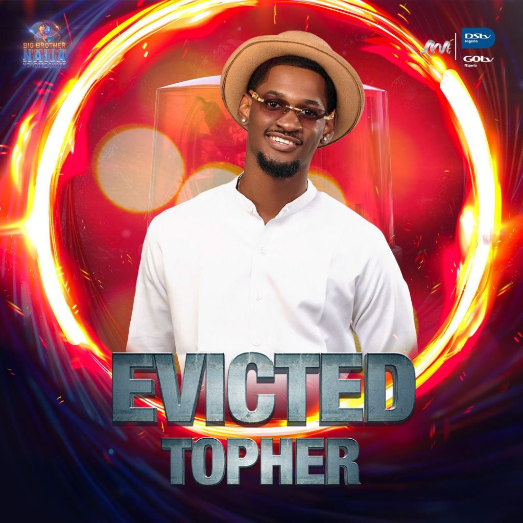 BBNaija star Topher standing with his back to the camera, wearing a white shirt and a brown hat. The text ‘EVICTED TOPHER’ is displayed in bold letters, with ‘EVICTED’ in red and ‘TOPHER’ in white. The background features vibrant red and orange hues with circular designs, adding a sense of motion and energy. Logos of BBNaija, GOtv, and DStv are present in the corners.