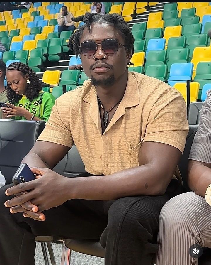 Social media activist Verydarkman seated in a stadium, engaging with his smartphone, exemplifying modern digital activism.