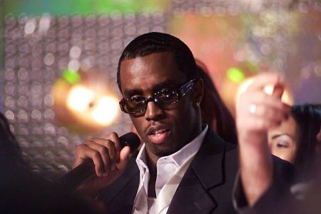 Sean “Diddy” Combs speaking at a public event, dressed in a stylish suit and addressing the audience with a confident expression.