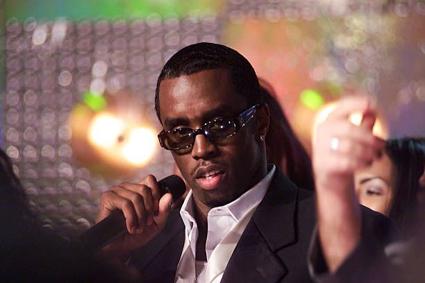 Sean “Diddy” Combs speaking at a public event, dressed in a stylish suit and addressing the audience with a confident expression.