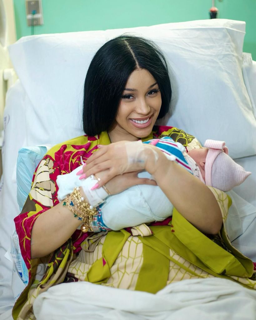 Cardi B holding her baby while wearing a smile