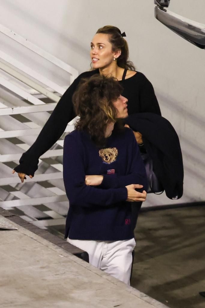 Miley Cyrus and her boyfriend Maxx Morando walking up stairs.