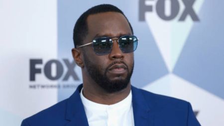 Diddy at a FOX network event, wearing a blue suit and white shirt, with the FOX logo in the background.