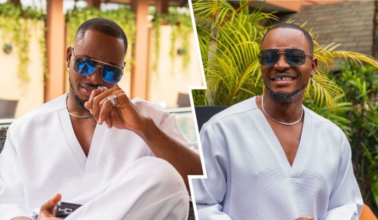 BBNaija star Kellyrae poses confidently in a white outfit, accessorized with sunglasses and jewelry. The backdrop features lush greenery, adding a vibrant touch to the scene. One side captures a playful smirk, while the other displays a warm smile, showcasing a charismatic personality.