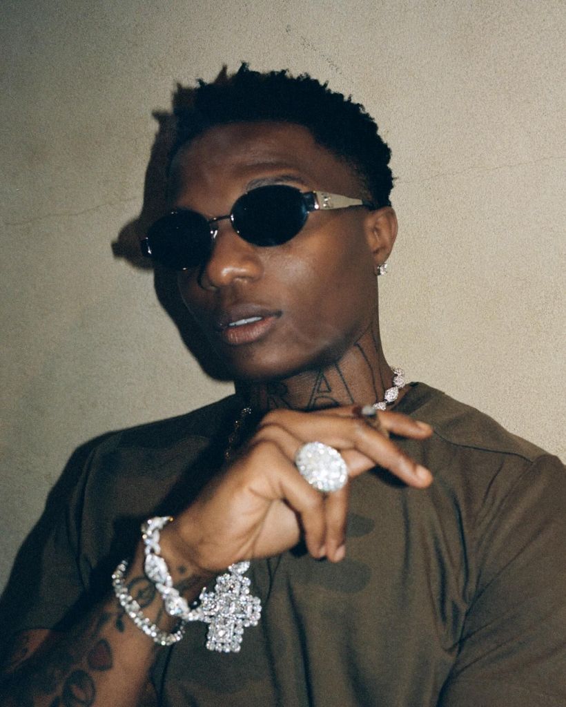 Wizkid sporting a dark shirt and intricate jewelry.