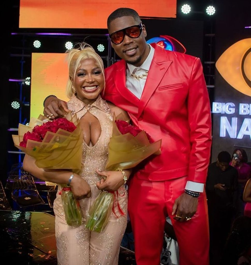 and Shaun celebrating on stage, with Wanni holding bouquets of flowers and flashing bright smiles, capturing a joyful moment from their post-BBNaija experience.
