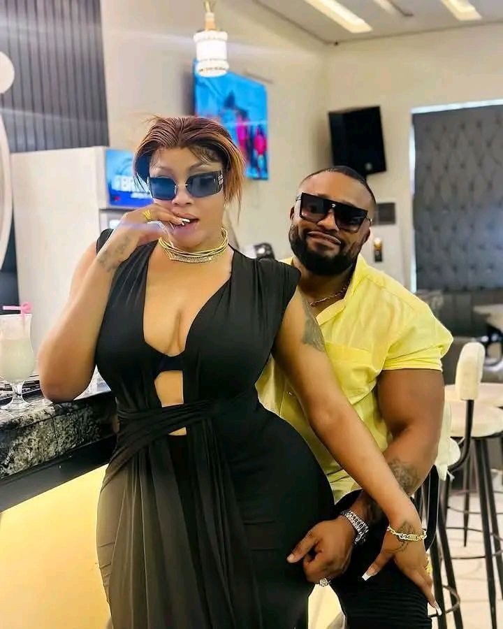 Angela Okorie in a black cut-out dress posing with her ex, Oil Money, who wears a yellow shirt.