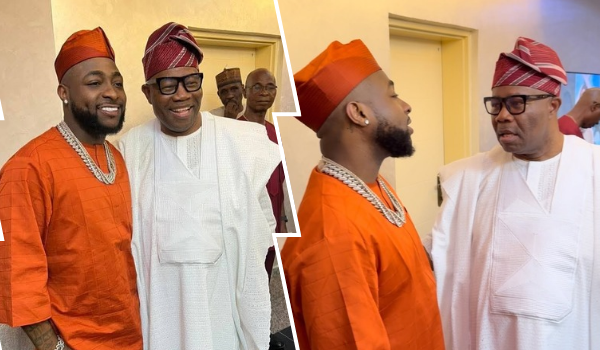 Davido, dressed in an orange traditional outfit with a matching cap and layered necklaces, stands alongside Senate President Godswill Akpabio, who wears a white traditional attire with a red and white cap, in a warmly lit indoor setting.