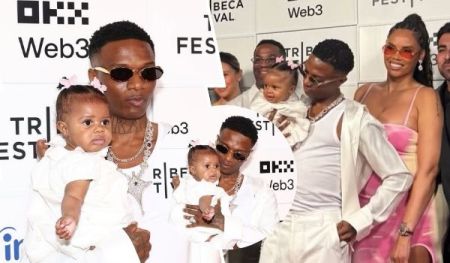 The collage showcases Nigerian singer Wizkid, his partner Jada, and their 6-month-old daughter Morayo at the premiere of his new documentary, “Wizkid: Long Live Lagos,” held at Web3 Fest. Wizkid is dressed in a white outfit with sunglasses and layered necklaces, holding Morayo, who wears a matching white dress adorned with a pink hair accessory. Jada stands nearby in a striking pink and white dress, while additional frames capture Wizkid with Morayo and another child against a backdrop featuring "Web3," "FEST," and "TRIBE" logos. The family’s coordinated white attire highlights their elegant and unified appearance at the event.