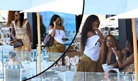 Michelle Obama and her daughters enjoy a vacation at an outdoor restaurant, dressed in vibrant summer outfits, surrounded by tables with glasses and umbrellas under a clear sky.
