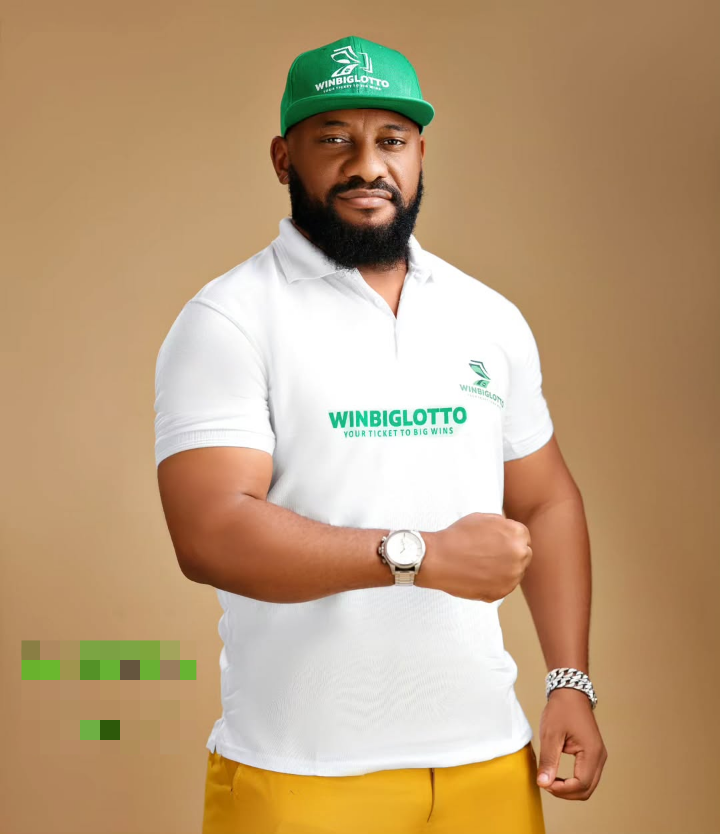 Nigerian actor Yul Edochie wears a white polo shirt and green cap branded with "WINBIGLOTTO" and the slogan "YOUR TICKET TO BIG WINS," confidently raising a clenched fist while sporting a silver watch and bracelet against a beige backdrop.