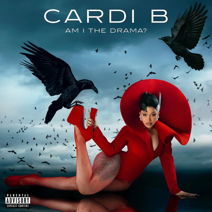 Cardi B poses in a bold red bodysuit with a dramatic collar, reclining on the ground with one leg raised and a raven perched on her stiletto. A stormy sky swirls behind her, filled with black birds, as the title “Am I The Drama?” looms above in bold white text.