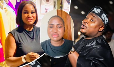 Cubana Chief Priest, dressed in a traditional black outfit with a patterned cap, stands beside Hellen Ati, who wears a sleeveless black top, both posing confidently in front of a vibrant display of colorful fashion pieces. In the center, another individual in a casual black shirt adds contrast against a warm wooden backdrop.