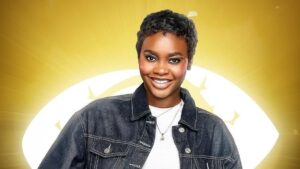 BBNaija Season 10 housemate Dede smiling in a denim jacket over a white top, posing against the signature Big Brother Naija eye logo backdrop.