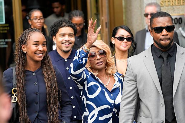 Diddy's mom waves while standing with his daughters, son, and a guard, all dressed in formal attire as they exit court building after verdict