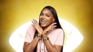BBNaija Season 10 housemate Thelma Lawson smiling brightly in a pink outfit, posing against the signature Big Brother Naija eye logo backdrop.