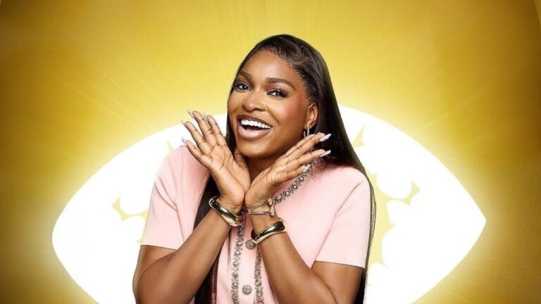 BBNaija Season 10 housemate Thelma Lawson smiling brightly in a pink outfit, posing against the signature Big Brother Naija eye logo backdrop.