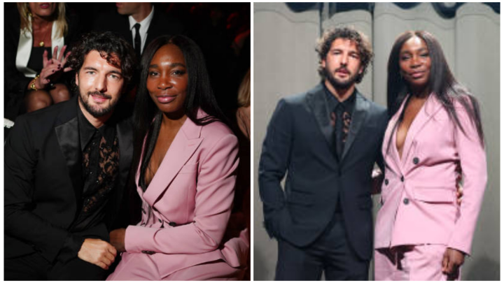 Venus Williams and her fiancé Andrea Preti pose together at a fashion event, with Venus dressed in a pink suit and Andrea in a black outfit.