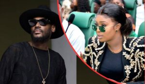 Singer 2baba, dressed in a black outfit with a gold chain and hat, poses beside Natasha Osawuru, who wears a black top with gold embroidery and matching earrings in a formal setting.