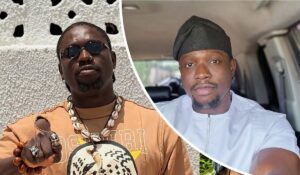 Activist VeryDarkMan appears in two contrasting settings: on the left, wearing a brown shirt labeled "OSUNRI" with bold accessories including a beaded necklace, rings, and a wooden bracelet against a textured white wall; on the right, dressed in a white traditional outfit and black cap, seated inside a vehicle with a view through the window.