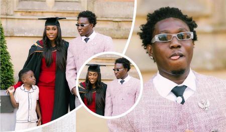 Zlatan poses in a pale pink suit beside Davita, dressed in a graduation gown over a red dress, celebrating an academic milestone. Their son Shiloh, wearing a white outfit with dark trim, stands between them in front of a stone building surrounded by greenery, capturing a joyful moment of family pride and achievement.