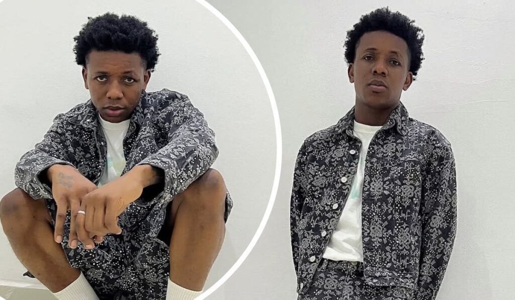 A collage featuring singer Small Doctor in two poses, wearing a matching black patterned jacket and shorts with a white shirt underneath, against a plain white background. One pose shows him crouching with hands extended, while the other depicts him standing with hands in pockets.