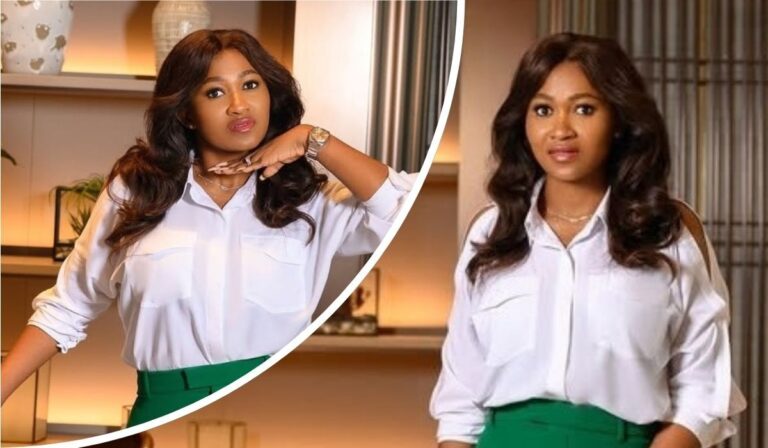 Mary Remmy Njoku poses confidently in a stylish white blouse and green skirt, accessorized with a watch and necklace, against a modern indoor backdrop with shelves and decor.