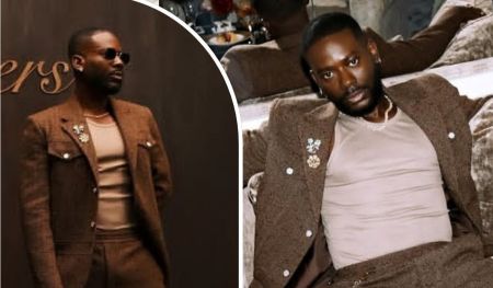 A collage showcases Nigerian musician Adekunle Gold in two stylish poses, wearing a brown suit with a floral pin and a light shirt, first standing against a wooden backdrop and then lounging on a plush couch.