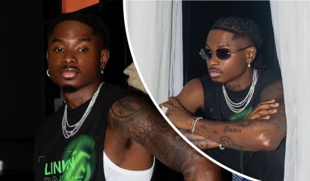 Lil Kesh spotted in a sleeveless black shirt, showcasing his tattoos and jewellery, as he poses confidently indoors.