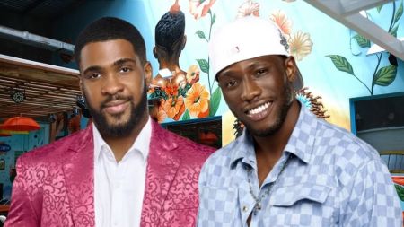 BBNaija Season 10 housemates Bright Morgan and Kayikunmi posing together in front of a vibrant floral wall mural inside the Big Brother Naija house. Bright Morgan wears a pink patterned suit while Kayikunmi smiles in a light blue checkered shirt and white cap.