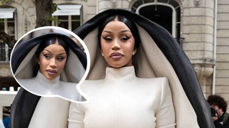 Cardi B wearing an avant-garde white gown with a dramatic black-and-white hood, attending a fashion event.