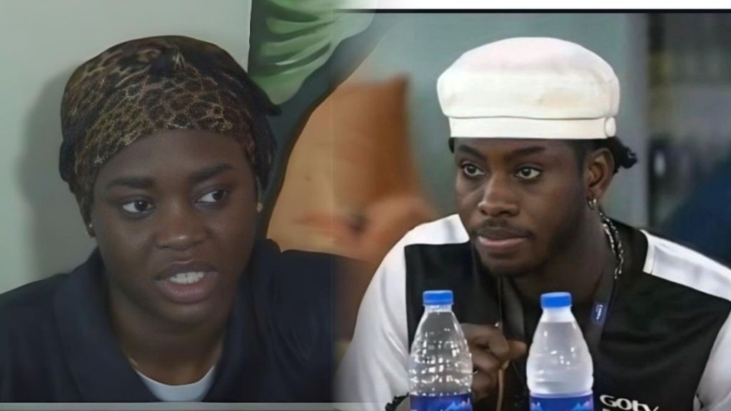 BBNaija Season 10 housemates Dede and Koyin pictured during a serious conversation inside the house; Dede wears a leopard-print headscarf while Koyin, dressed in a black-and-white shirt with a white cap, sits at a table with water bottles.