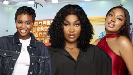 BBNaija Season 10 housemates Dede, Sultana, and Mode pose in the Big Brother house arena, with Dede in a denim jacket, Sultana in a black outfit, and Mode in a red halter-neck dress.