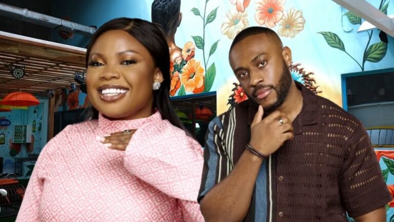 BBNaija Season 10 housemates Doris and Lola posing together in the Big Brother Naija house. Doris is smiling in a pink patterned outfit, while Lola stands beside her in a dark striped shirt with his hand on his chin. A colourful floral mural forms the background.