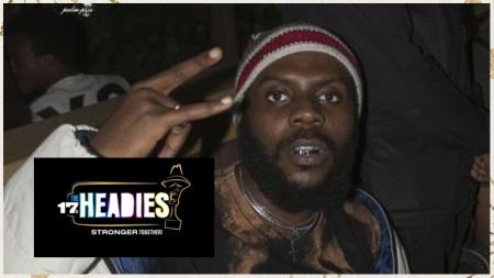 Nigerian rapper Odumodublvck makes a bold hand gesture while posing for the camera, with the 17th Headies Awards logo, themed “Stronger Together!”, displayed beside him.