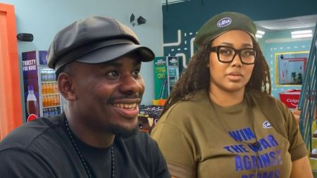 BBNaija Season 10 housemates Victory and Gigi Jasmine inside the Big Brother Naija house, with Victory smiling in a black leather cap and T-shirt, and Gigi Jasmine wearing glasses, a green beret, and a green “Win the War Against Germs” T-shirt.