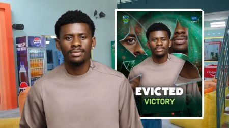 BBNaija Season 10 housemate Victory is seen in a neutral-toned outfit inside the Big Brother Naija house. An inset image shows his official eviction card with the word “Evicted” boldly written above his name.