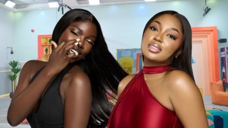 BBNaija Season 10 housemates Zita and Mide strike playful and confident poses inside the Big Brother house arena, with a bright and colourful set behind them.