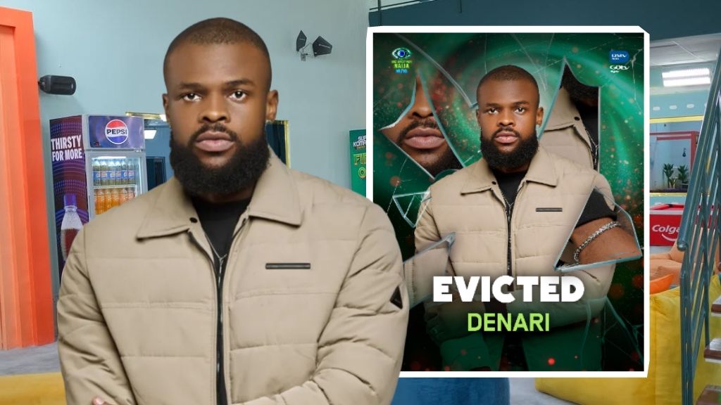 BBNaija Season 10 housemate Denari in a beige jacket, standing in front of the eviction announcement card with the word “Evicted” boldly written across his photo.