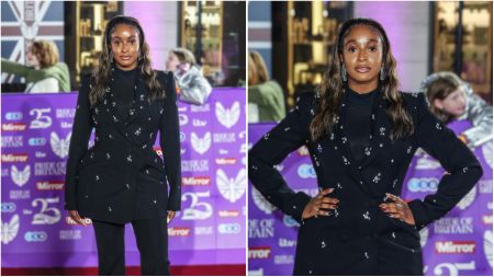 Nigerian DJ and philanthropist DJ Cuppy poses on the red carpet at an event, wearing a black embellished blazer with matching trousers, styled with wavy hair and statement earrings.