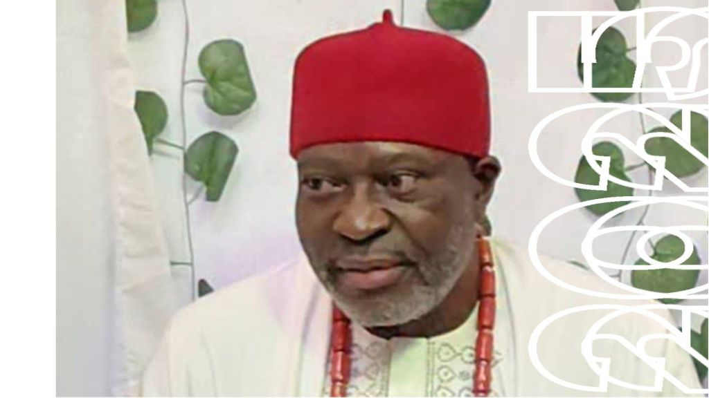 Veteran Nollywood actor Kanayo O. Kanayo wearing a traditional red cap and white attire, with coral beads around his neck, pictured during an interview setting.