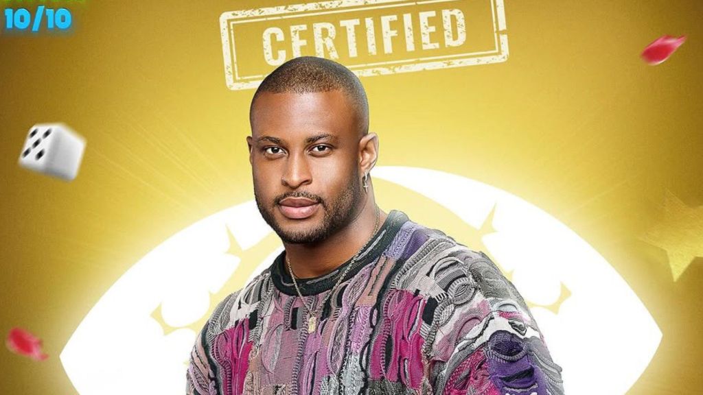 BBNaija Season 10 housemate Kaybobo poses in a patterned multicoloured sweater against a golden background with the show’s “Certified” stamp above him.