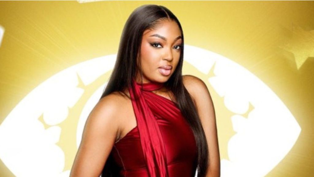 BBNaija housemate Mide poses in a red sleeveless outfit with long straight hair against the show’s signature yellow backdrop.