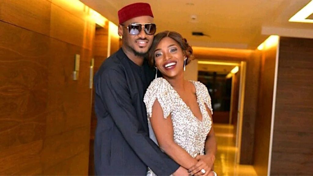 Nigerian singer 2Face Idibia and his wife Natasha Idibia share a warm embrace in a hallway, smiling happily at the camera.