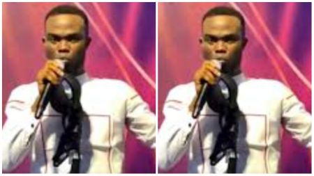 Pastor Isaac Josiah speaking into a microphone while holding a cap, dressed in a white shirt with a pink and purple stage backdrop.