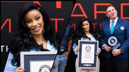 Cardi B smiles while holding her Guinness World Records certificate, celebrating her new achievement at an official recognition event.
