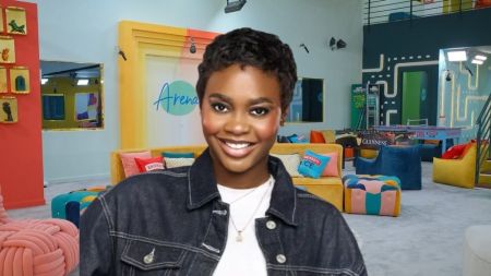 BBNaija Season 10 housemate Dede smiles brightly inside the Big Brother Naija house lounge, wearing a denim jacket over a white top.