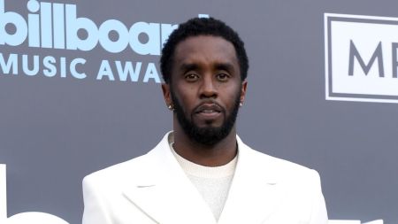American rapper and entrepreneur Sean “Diddy” Combs poses in a white suit and cream knit top on the red carpet at the Billboard Music Awards.
