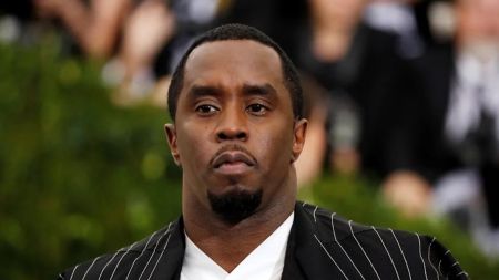 American rapper and music mogul Diddy, dressed in a black pinstripe suit over a white shirt, looks serious while attending a public event.
