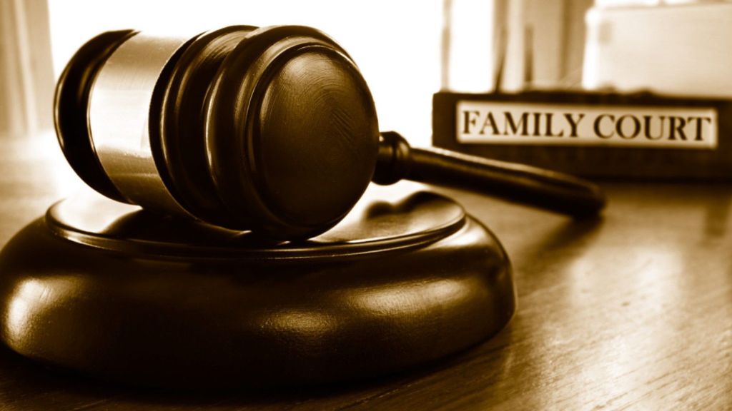 A close-up of a wooden judge’s gavel resting on a sound block beside a sign labeled “Family Court,” symbolizing justice and legal proceedings in family law
